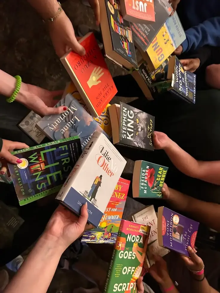 Hands holding up a pile of different novels